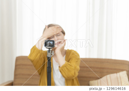 リビングで動画配信をするシニア女性 129614616