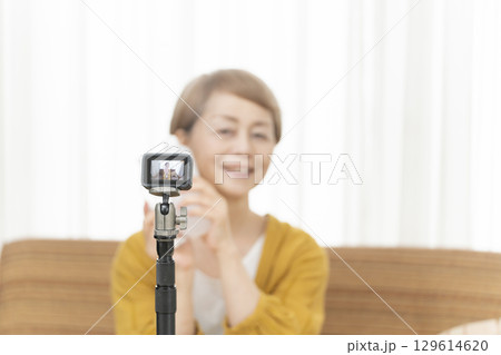 リビングで動画配信をするシニア女性 129614620