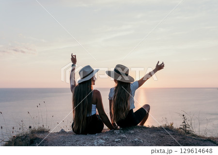 Two Women in Hats Enjoying Sunset Over the Sea Two Women in Hats Enjoying Sunset Over the Sea 129614648