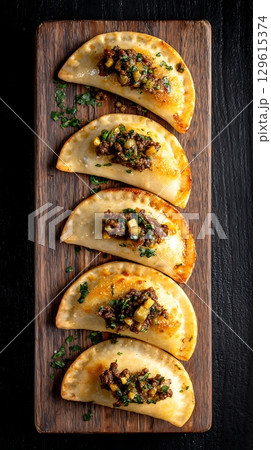 Delicious Empanadas Served on a Rustic Wooden Board with Fresh Parsley. 129615374
