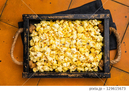 Cheese and salty popcorn in wooden tray. orange background. top view Cheese and salty popcorn in wooden tray. orange background. top view 129615673