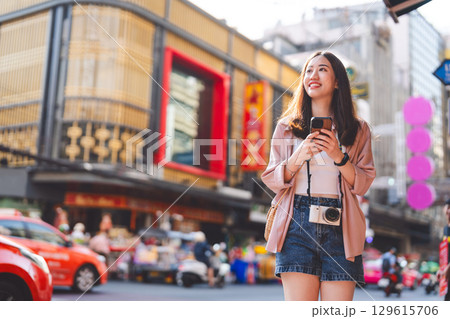 Adult asian woman traveler in urban city using smartphone travel guide 129615706