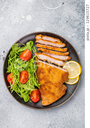 Fried Weiner schnitzel steak, veal breaded meat with salad on a plate. grey background. top view 129615727