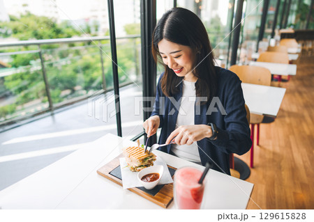 Asian woman healthy eating breakfast sandwich food diet meal at indoor cafe Asian woman healthy eating breakfast sandwich food diet meal at indoor cafe 129615828