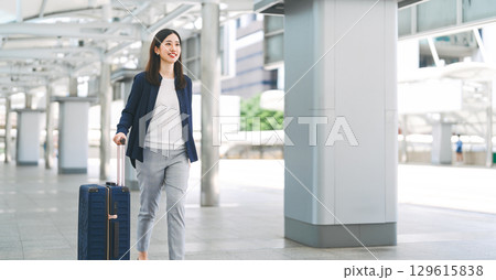 Adult business asian woman walking with luggage for work and travel at station platform on day 129615838