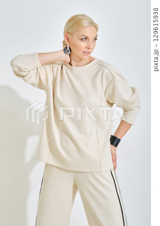 Stylish woman poses in casual fashion outfit in a minimalistic studio setting 129615938