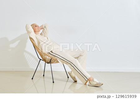 Relaxing in a modern chair, a woman enjoys a quiet moment in a minimalist indoor space Relaxing in a modern chair, a woman enjoys a quiet moment in a minimalist indoor space 129615939