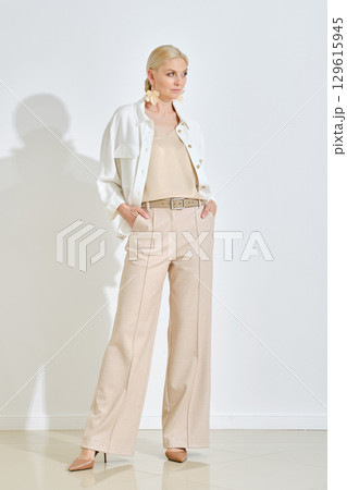Fashionable woman in elegant outfit poses against a light background in a stylish setting 129615945