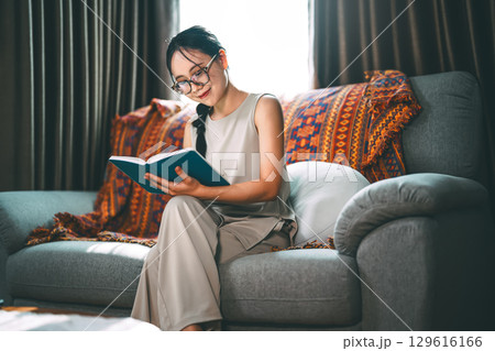 Adult asian woman reading book on sofa relax routines everyday at living room 129616166