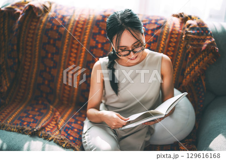 Adult asian woman reading book on sofa relax routines everyday at living room 129616168