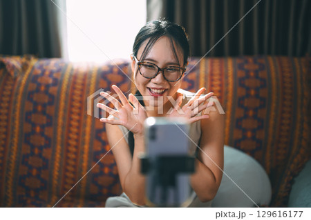 Asian woman influencer using smartphone wireless technology communication customer engagement online marketing 129616177