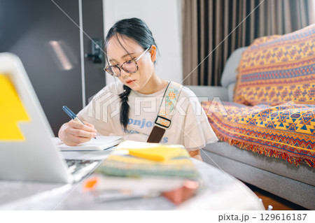 Young adult asian woman wearing headphones playing electric guitar music education online learning Young adult asian woman wearing headphones playing electric guitar music education online learning 129616187