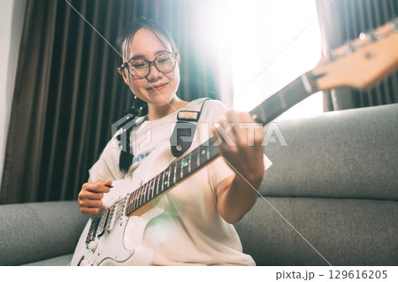 Young asian woman playing electric guitar music at home studio 129616205