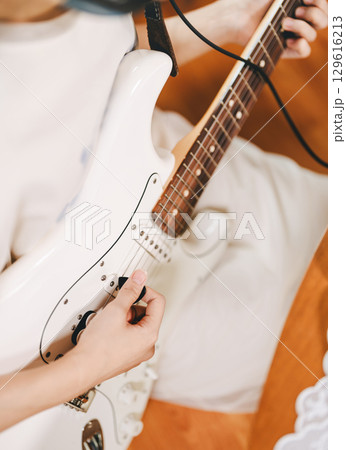 Focus hand of woman playing electric guitar Focus hand of woman playing electric guitar 129616213