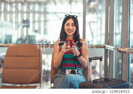 Tourist woman passenger at international airport terminal for holidays travel hand holding camera Tourist woman passenger at international airport terminal for holidays travel hand holding camera 129616422