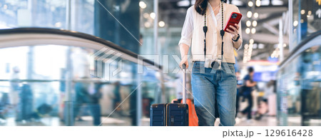 Standing passenger woman to transit with travel luggage and camera at international airport journey Standing passenger woman to transit with travel luggage and camera at international airport journey 129616428