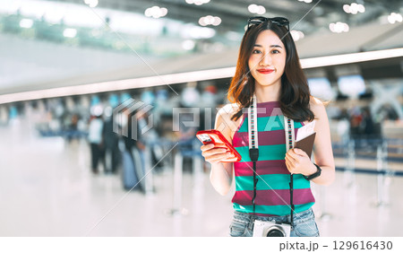 Portrait of tourist woman eye looking at camera with travel passport at airport terminal 129616430