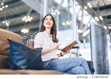 Adult passenger business asian woman sitting with luggage for global trip at airport terminal 129616448