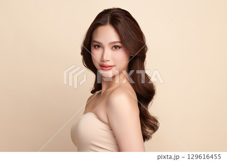 A beautiful young Asian woman with clean, fresh skin against a beige background. Skincare, facial treatment, cosmetology, beauty, and spa. An elegant portrait of an Asian woman. A beautiful young Asian woman with clean, fresh skin against a beige background. Skincare, facial treatment, cosmetology, beauty, and spa. An elegant portrait of an Asian woman. 129616455