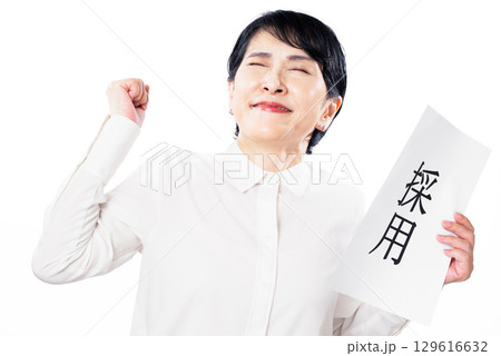採用と書かれた紙を持ち嬉しそうにガッツポーズをするシニア女性 129616632