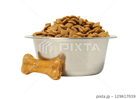 Kibble in a silver bowl with a chew bone nearby, isolated on white, PNG 129617039