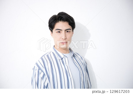 白背景で真剣な表情のカジュアルなシャツを着た男性のカメラ目線 129617203