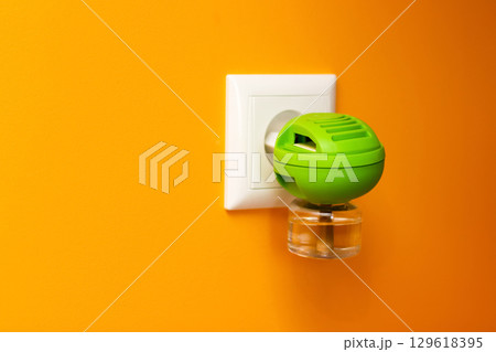a fumigator plugged into a socket on a clean yellow background. protection against mosquito and insect bites, is perfect for a summer or pest control theme a fumigator plugged into a socket on a clean yellow background. protection against mosquito and insect bites, is perfect for a summer or pest control theme 129618395