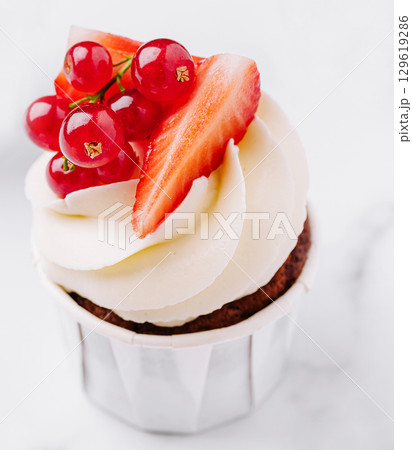 Delicious cupcake topped with fresh strawberries and red currants 129619286