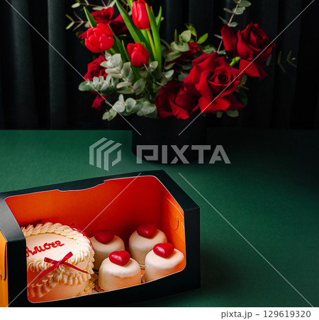 Delicious cake and sweet treats with a bouquet on a green table Delicious cake and sweet treats with a bouquet on a green table 129619320