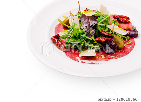Fresh salad with cured meat and assorted greens served on a white plate 129619366