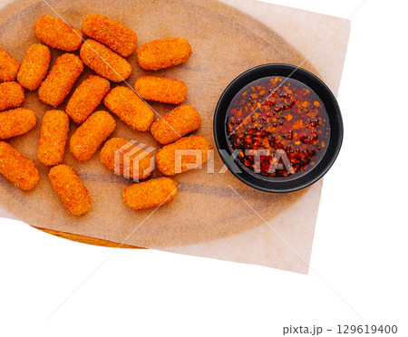 Golden crispy croquettes served on a wooden platter with dipping sauce 129619400