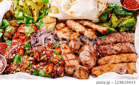 Succulent grilled meats and vibrant vegetables arranged on a platter Succulent grilled meats and vibrant vegetables arranged on a platter 129619433