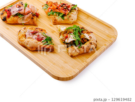 Artisan flatbreads with fresh toppings served on a wooden tray Artisan flatbreads with fresh toppings served on a wooden tray 129619482