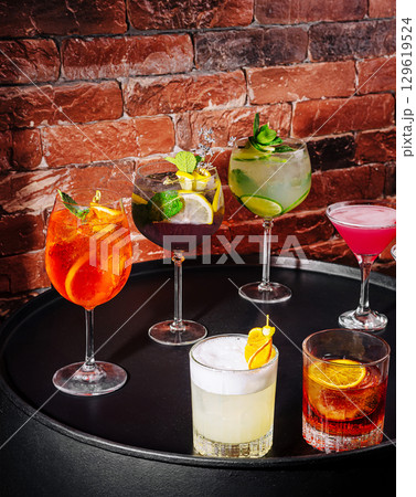 Colorful cocktails displayed on a circular table against a brick background 129619524