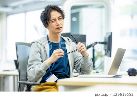 眼精疲労　デスクで頭を抱える30代のビジネスマン 129619552
