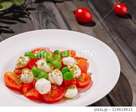 Fresh mozzarella and tomato salad with basil on wooden table Fresh mozzarella and tomato salad with basil on wooden table 129619612