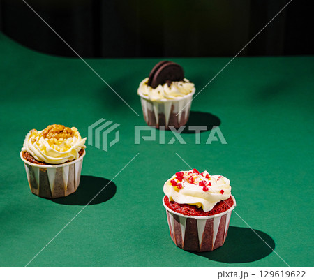 Colorful cupcakes arranged on a green surface during bright lighting 129619622