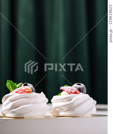 Delicious meringue desserts decorated with fresh fruit placed on a table Delicious meringue desserts decorated with fresh fruit placed on a table 129619623