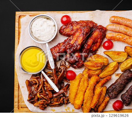 Savory platter with assorted meats and sauces served on wooden board 129619626