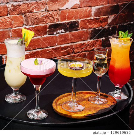 Colorful cocktails served on a wooden platter at a vibrant bar setting Colorful cocktails served on a wooden platter at a vibrant bar setting 129619656