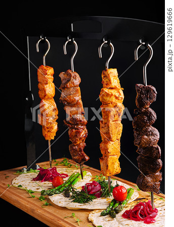 Delicious skewers served on a wooden platter with fresh vegetables and herbs Delicious skewers served on a wooden platter with fresh vegetables and herbs 129619666