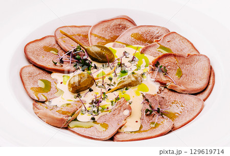 Thinly sliced meat served with tangy sauce and garnished with herbs 129619714