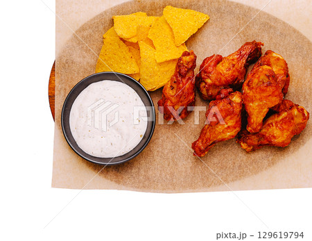 Buffalo wings with tortilla chips and ranch dressing served on a platter Buffalo wings with tortilla chips and ranch dressing served on a platter 129619794