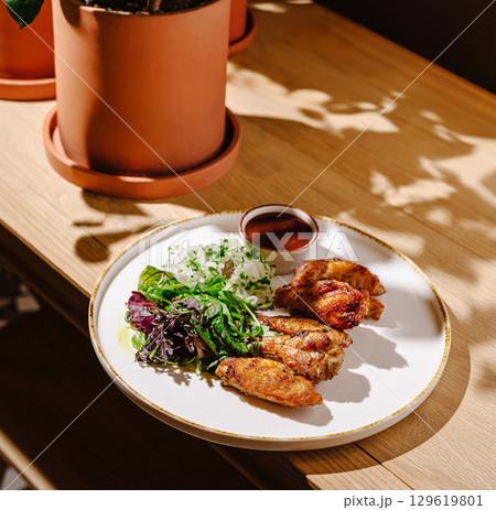 Delicious chicken wings served with fresh salad and dipping sauce Delicious chicken wings served with fresh salad and dipping sauce 129619801