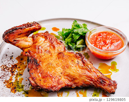 Grilled chicken leg served with salsa and fresh herbs on a plate Grilled chicken leg served with salsa and fresh herbs on a plate 129619805