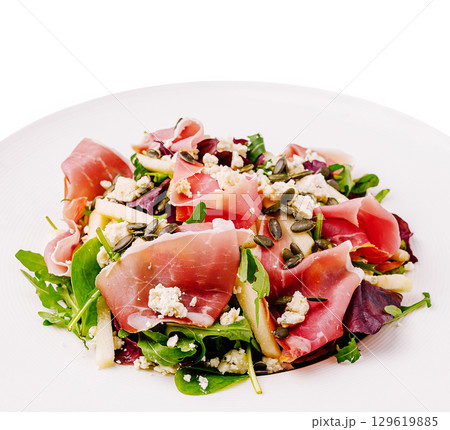 Fresh salad with prosciutto, apple, and seeds served on a white plate Fresh salad with prosciutto, apple, and seeds served on a white plate 129619885