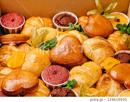 Delicious assortment of pastries and desserts in a bakery box in daylight Delicious assortment of pastries and desserts in a bakery box in daylight 129619930