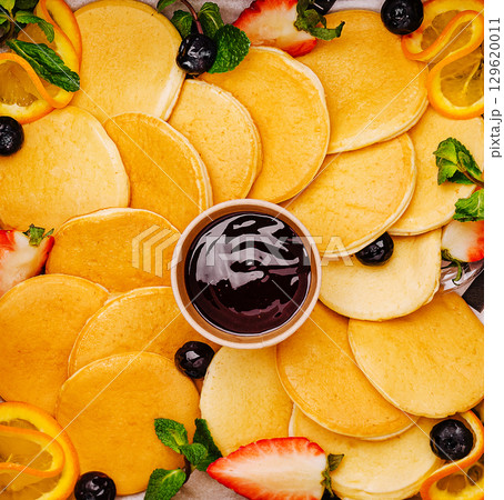 Delicious pancakes served with fresh fruit and berry sauce on a colorful platter 129620011