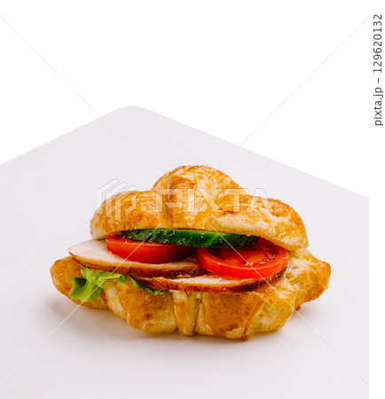 Fresh croissant sandwich featuring turkey, tomatoes, and lettuce 129620132