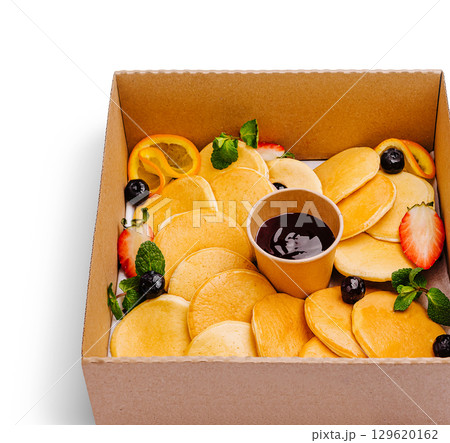 Delicious mini pancakes served with fruit and syrup in a takeout box 129620162